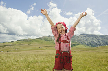 Italy, Seiseralm, Girl (8-9) in meadow cheering, arms up, portrait - WESTF13378