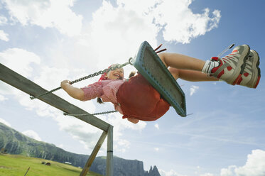 Italy, Seiseralm, Girl (8-9) sitting on swing, portrait - WESTF13373