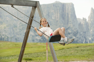 Italy, Seiseralm, Girl (6-7) sitting on swing, portrait - WESTF13371