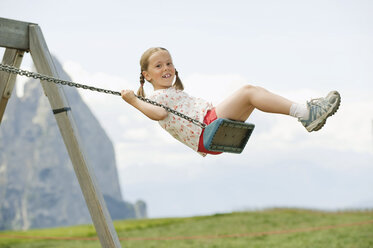 Italy, Seiseralm, Girl (6-7) sitting on swing, portrait - WESTF13370