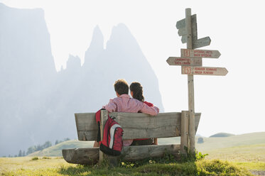 Italy, South Tyrol, Seiseralm, Couple sitting on bench, rear view - WESTF13725