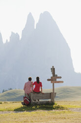 Italy, South Tyrol, Seiseralm, Couple sitting on bench, rear view - WESTF13723