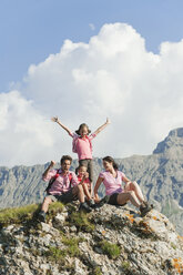 Italy, South Tyrol, Family sitting on rock, cheering, portrait - WESTF13714