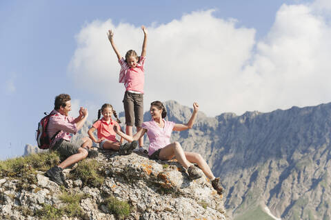 Italien, Südtirol, Familie sitzt auf Felsen, Mann fotografiert, lizenzfreies Stockfoto