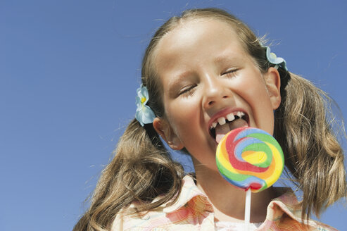 Italy, South Tyrol, Girl (6-7) licking lollypop, portrait, close-up - WESTF13664