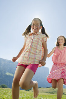 Italien, Südtirol, Seiseralm, Zwei Mädchen (6-7) (10-11) laufen im Feld - WESTF13659