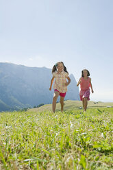 Italien, Südtirol, Seiseralm, Zwei Mädchen (6-7) (10-11) laufen im Feld - WESTF13658