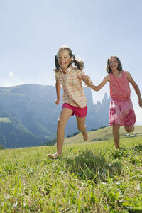 Italien, Südtirol, Seiseralm, Zwei Mädchen (6-7) (10-11) laufen im Feld - WESTF13657