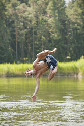 Italy, South Tyrol, Man jumping into lake - WESTF13635