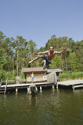 Italy, South Tyrol, Man jumping into lake - WESTF13631