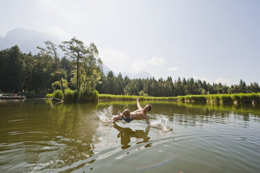 Italy, South Tyrol, Man jumping into lake - WESTF13627