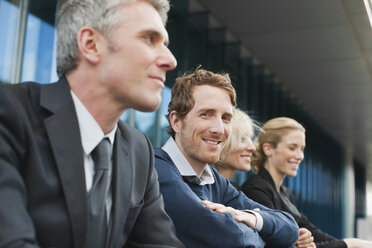 Germany, Hamburg, Four Business people sitting on steps in front of office building - WESTF13884