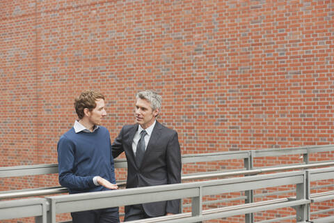 Germany, Hamburg, Two businessmen talking in front of brick wall stock photo