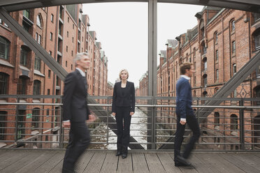 Germany, Hamburg, Two Businessmen crossing bridge, Businesswoman in background - WESTF13868
