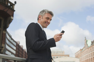 Germany, Hamburg, Businessman using mobile phone, smiling, portrait - WESTF13849