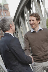 Germany, Hamburg, Two businessmen shaking hands, smiling, portrait - WESTF13842