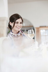 Frau im Restaurant mit einem Glas Weißwein in der Hand, lächelnd, Porträt - WESTF13812
