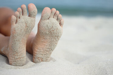 Italy, Sardinia, Person lying on beach, sandy feet - MBEF00013