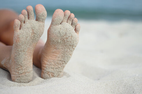 Italien, Sardinien, Person liegend am Strand, sandige Füße - MBEF00013