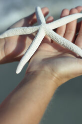 Italy, Sardinia, Person holding star fish - MBEF00007