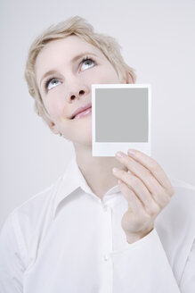 Frau mit Polaroidbild in der Hand, nach oben blickend, Porträt - TCF01268