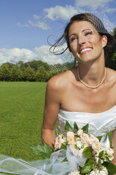 Germany, Bavaria, Bride in park holding bunch of flowers, portrait, close-up - NHF01155