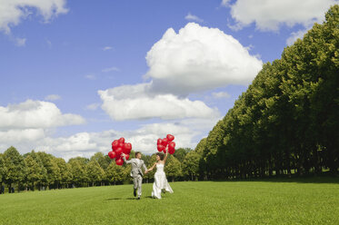 Deutschland, Bayern, Braut und Bräutigam halten rote Luftballons, im Freien - NHF01148