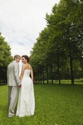 Germany, Bavaria, Bridal couple in park hand in hand, smiling, portrait - NHF01142