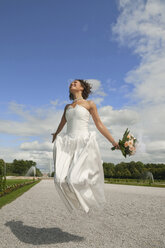 Germany, Bavaria, Bride in park jumping in air, smiling, portrait - NHF01134