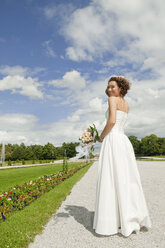 Deutschland, Bayern, Braut im Park mit Blumenstrauß, lächelnd, Porträt - NHF01128