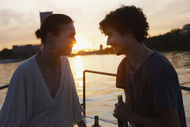 Germany, Berlin, Young couple on boat, holding bottles, side view, portrait - VVF00103