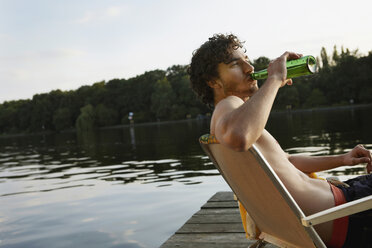 Deutschland, Berlin, Junger Mann trinkt ein Flaschengetränk, Seitenansicht, Porträt - VVF00101