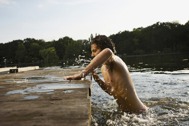 Germany, Berlin, Young man climbing on jetty, side view - VVF00094