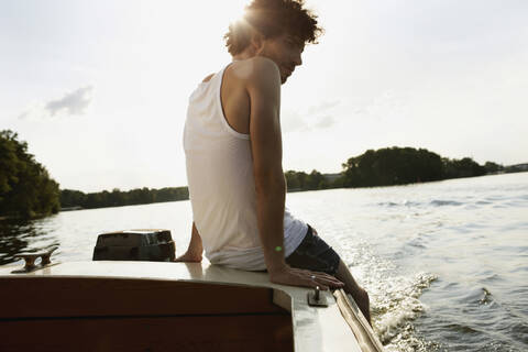 Germany, Berlin, Young man sitting on motor boat stock photo