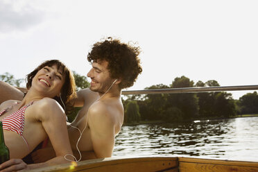 Germany, Berlin, Young couple on motor boat, man wearing headphones, portrait, close-up - VVF00072