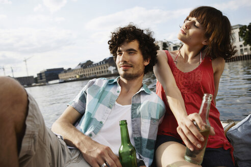 Germany, Berlin, Young couple on motor boat, holding bottles, portrait, close-up - VVF00064