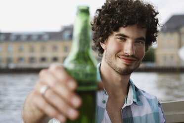 Germany, Berlin, Young man holding bottle, portrait, close-up - VVF00057