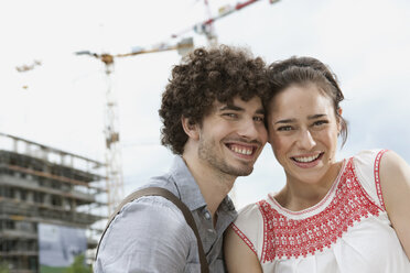 Germany, Berlin, Young couple in front of new building, cranes in background - VVF00022