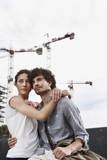 Deutschland, Berlin, Junges Paar vor neuem Gebäude, Kräne im Hintergrund - VVF00016