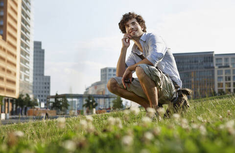 Germany, Berlin, Young man using mobile phone, smiling, portrait stock photo