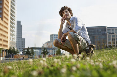 Germany, Berlin, Young man using mobile phone, smiling, portrait - VVF00007