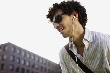 Deutschland, Berlin, Junger Mann beim Hören eines MP3-Players - VVF00002