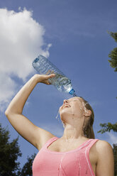 Deutschland, Berlin, Junge Frau gießt sich Wasser über das Gesicht, Porträt - SKF00143