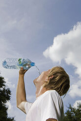 Germany, Berlin, Young man drinking from water bottle, portrait - SKF00141