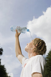 Germany, Berlin, Young man pouring water over face, side view, portrait - SKF00140