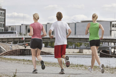 Deutschland, Berlin, Drei Personen beim Joggen in der Stadt, Rückansicht - SKF00125