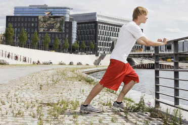 Germany, Berlin, Young man stretching on railing - SKF00117