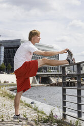Deutschland, Berlin, Junger Mann streckt Bein auf Geländer - SKF00115