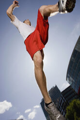 Germany, Berlin, Young man jumping in air, low angle view - SKF00110