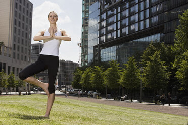 Germany, Berlin, Young woman exercising yoga, smiling, portrait - SKF00105